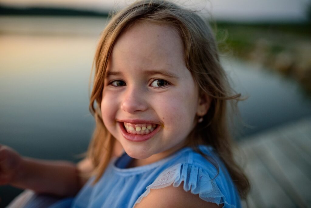 The little girl smiles and shows her baby teeth. Close-up.