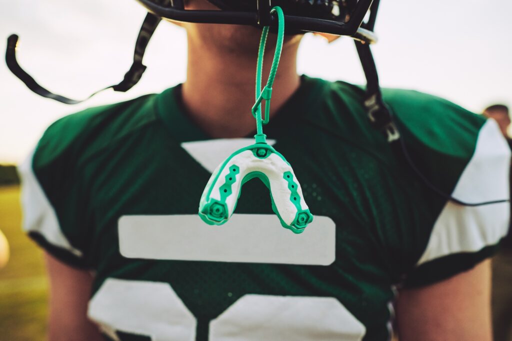 Youth football player wearing a mouthguard, highlighting the importance of dental protection for kids in sports at Kids Smiles Pediatric Dentistry in St. Louis.